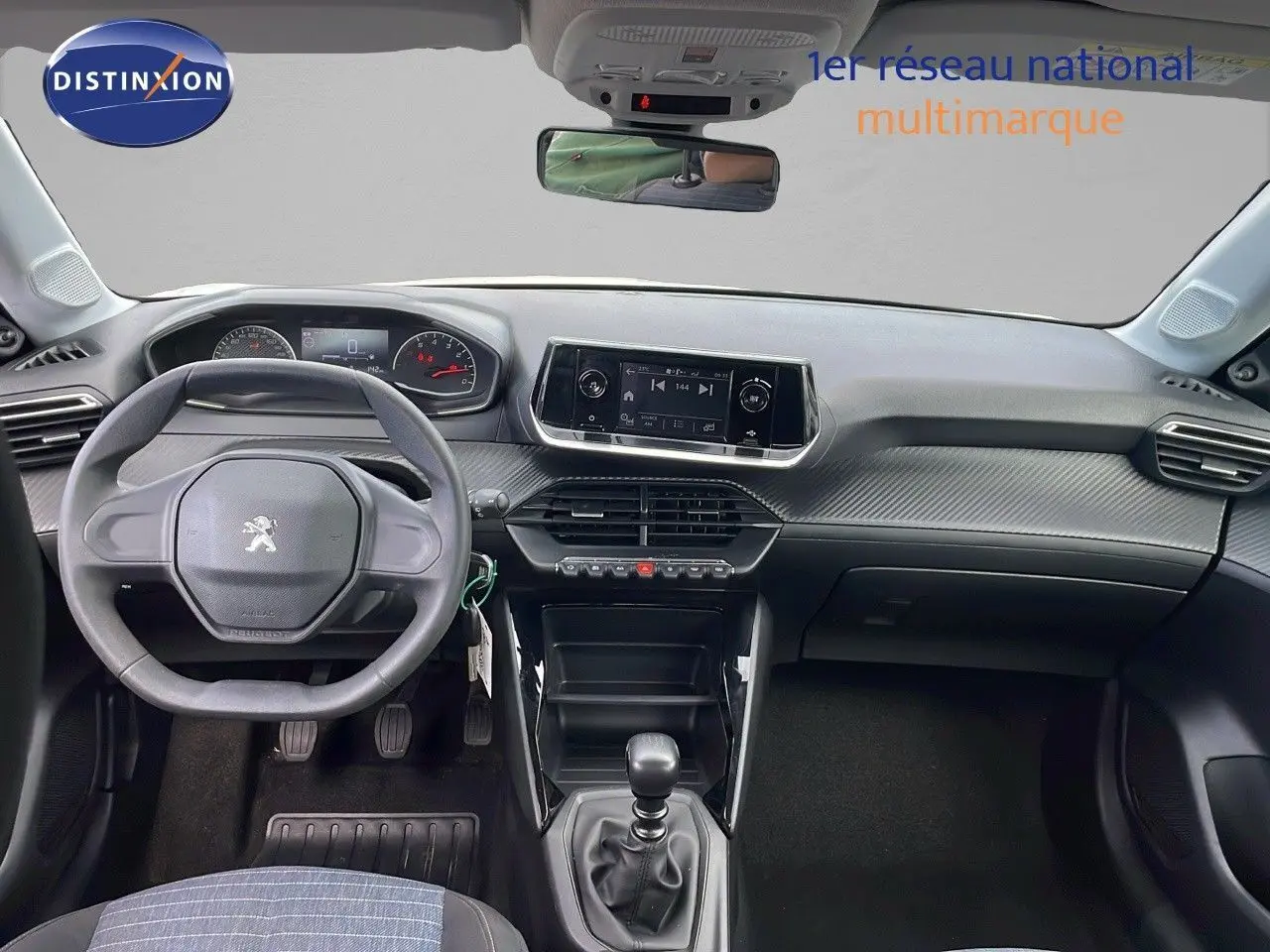 Vue intérieure du tableau de bord et volant de la Peugeot 208 blanche banquise version Société 2021 avec boîte manuelle.