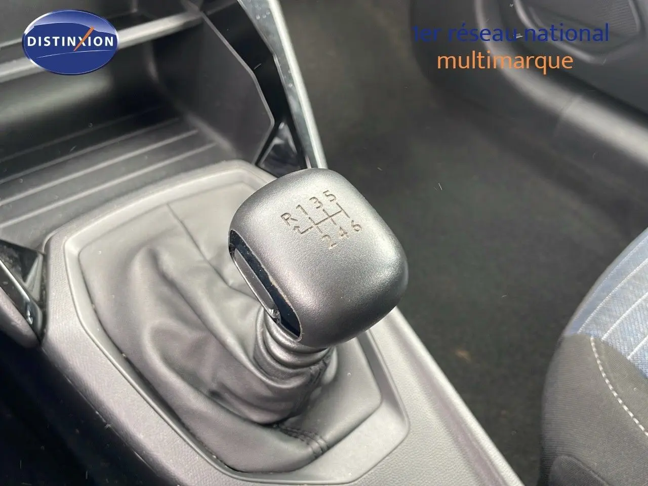 Le levier de vitesses manuel 6 rapports de la Peugeot 208 blanche, avec console et partie du siège côté passager.