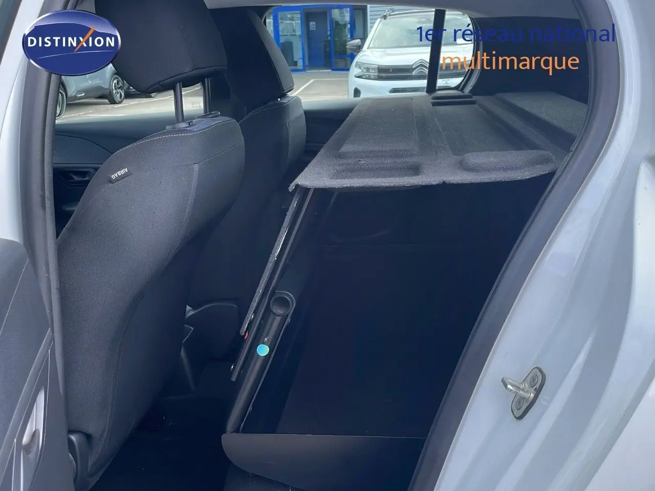 Intérieur arrière côté droit d'une Peugeot 208 blanc banquise 2021 avec banquette rabattue et sellerie noire.