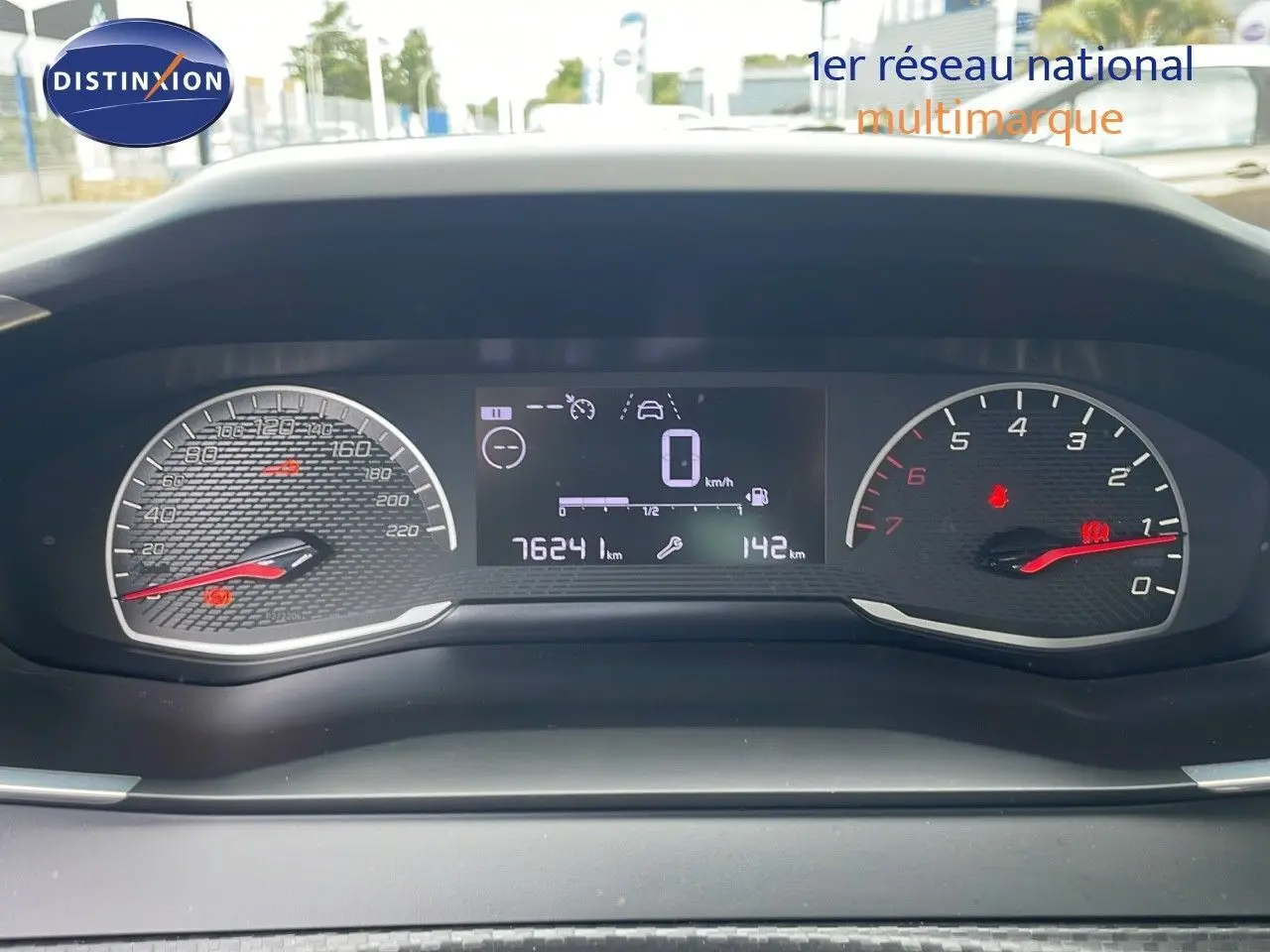 Tableau de bord numérique de Peugeot 208 blanc banquise, affichant 76241 km et vitesse à zéro, vue frontale rapprochée.