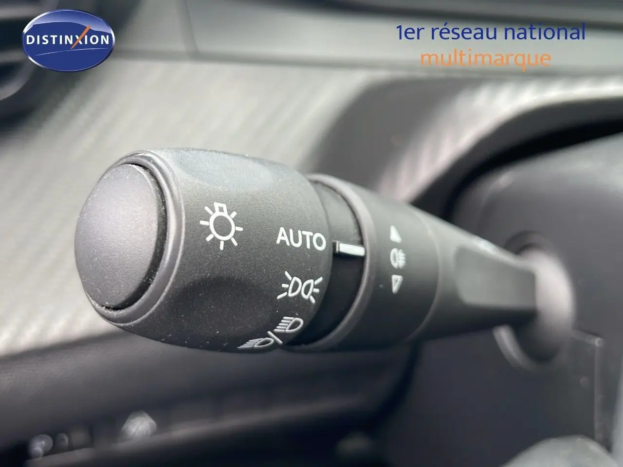 Gros plan sur la commande des phares de la Peugeot 208 blanche, version Société 1.5 HDI 2021, intérieur noir.