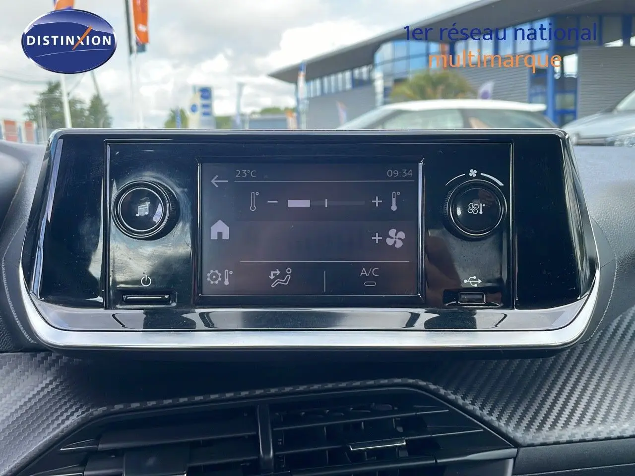 Écran tactile de climatisation et commandes dans l'habitacle d'une Peugeot 208 blanc banquise, vue de face.