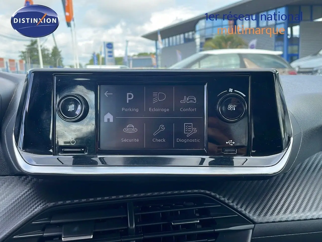Écran tactile central du tableau de bord de la Peugeot 208 blanc banquise, avec commandes de confort et sécurité affichées.