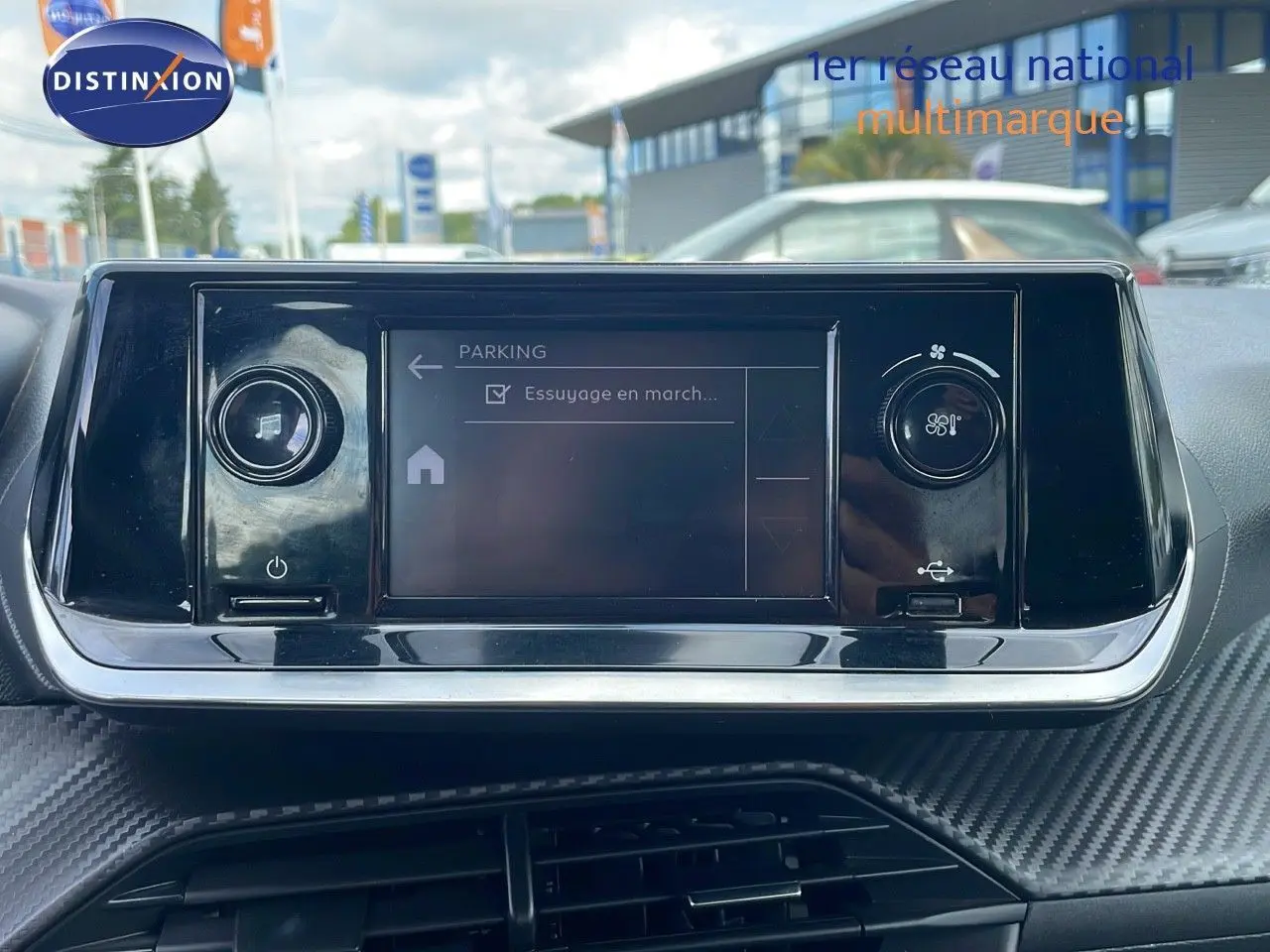 Écran tactile central du tableau de bord d'une Peugeot 208 blanc banquise, avec commandes de climatisation visibles.