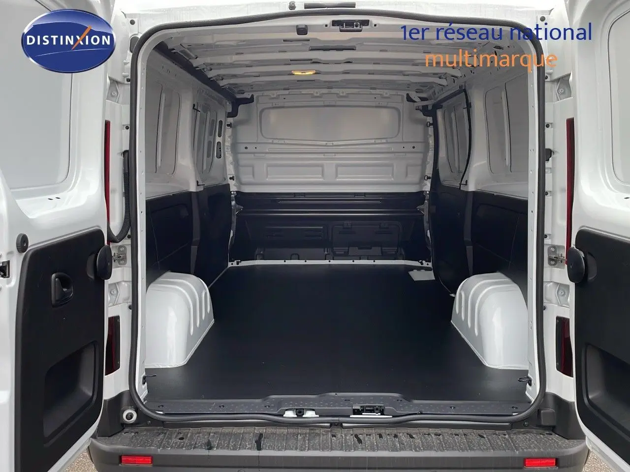 Vue arrière ouverte du Renault Trafic Fourgon blanc glacier L2H1, montrant l'espace de chargement vide et les portes battantes ouvertes.