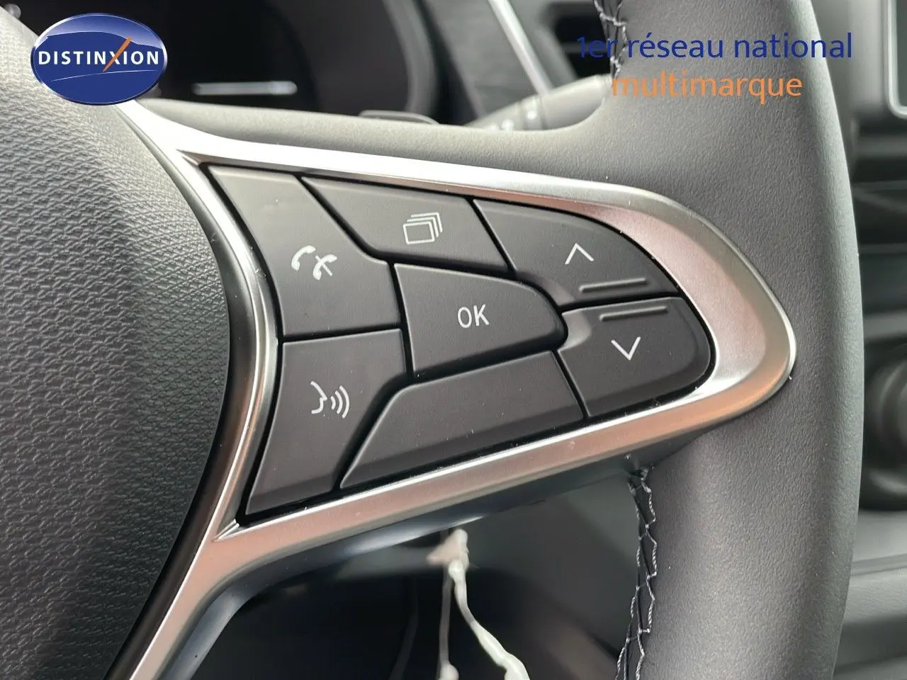 Gros plan sur les commandes multifonctions du volant en cuir noir du Renault Trafic Fourgon blanc glacier 2025.