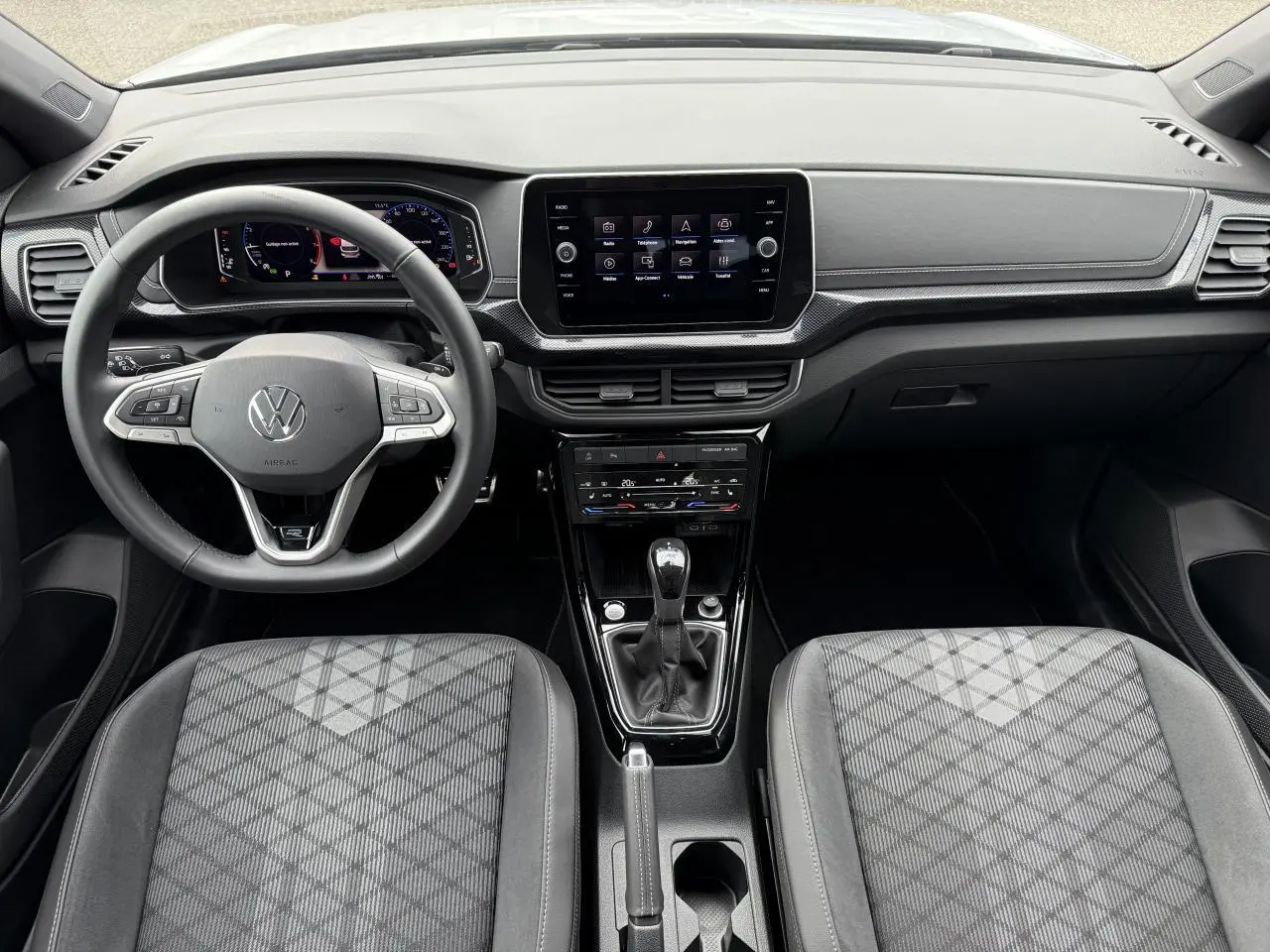 Intérieur du Volkswagen T-Cross 2025, vue frontale sur le tableau de bord et volant multifonction noir.
