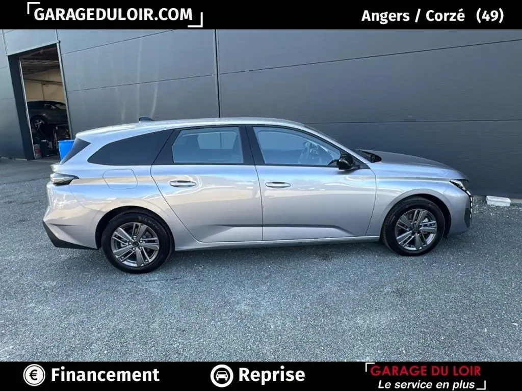 Profil droit d’une Peugeot 308 gris clair 2023, break avec jantes alliage et vitres teintées.