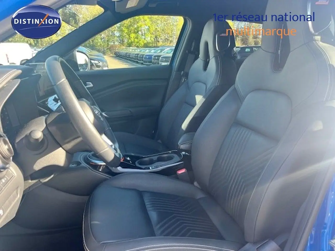 Vue intérieure côté conducteur du Nissan Juke 2025 bleu magnétique, sièges en cuir noir et volant multifonction.