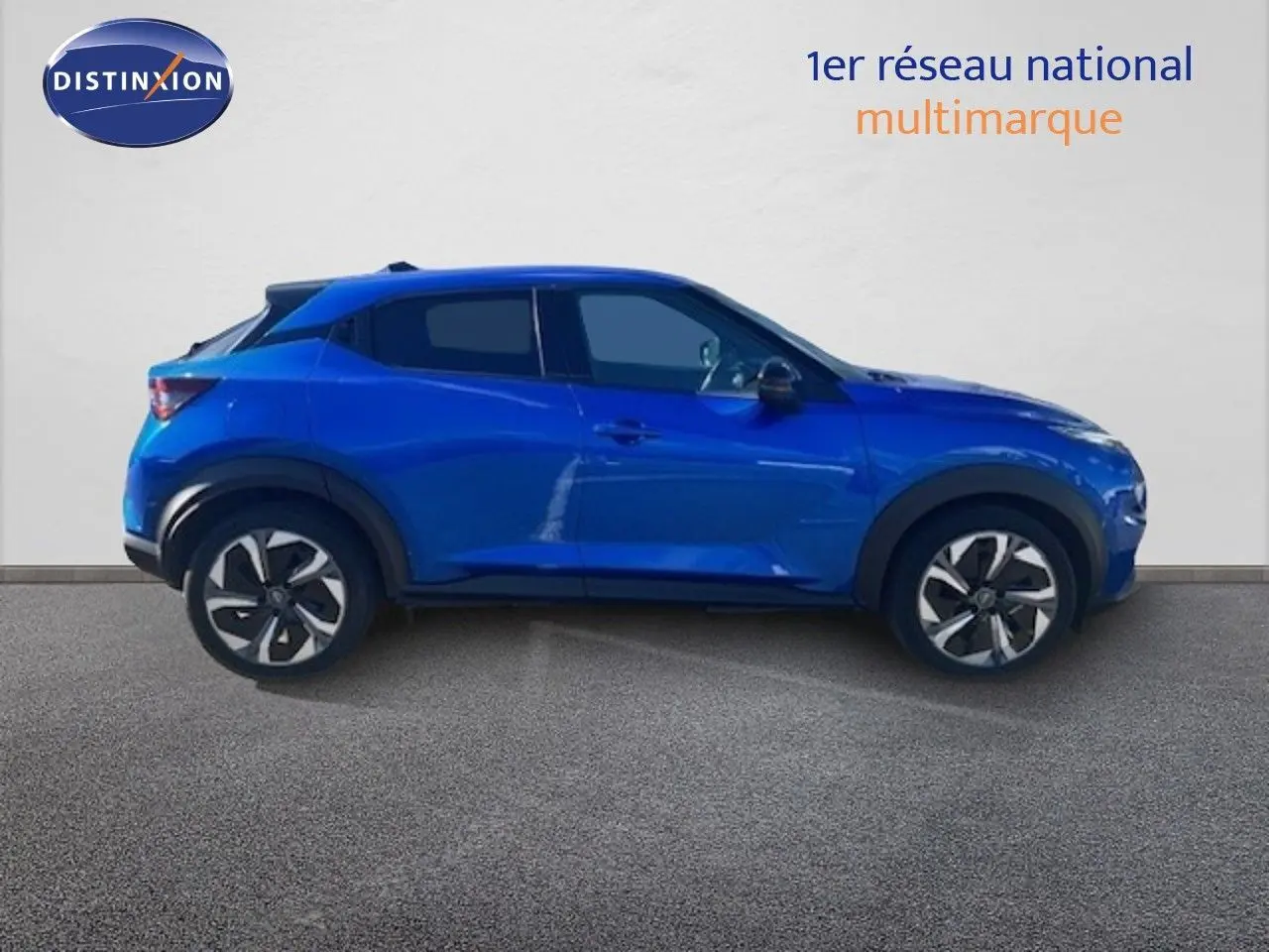 Vue de profil côté gauche d'un Nissan Juke 2025 bleu magnétique métallisé avec jantes distinctives et toit noir.