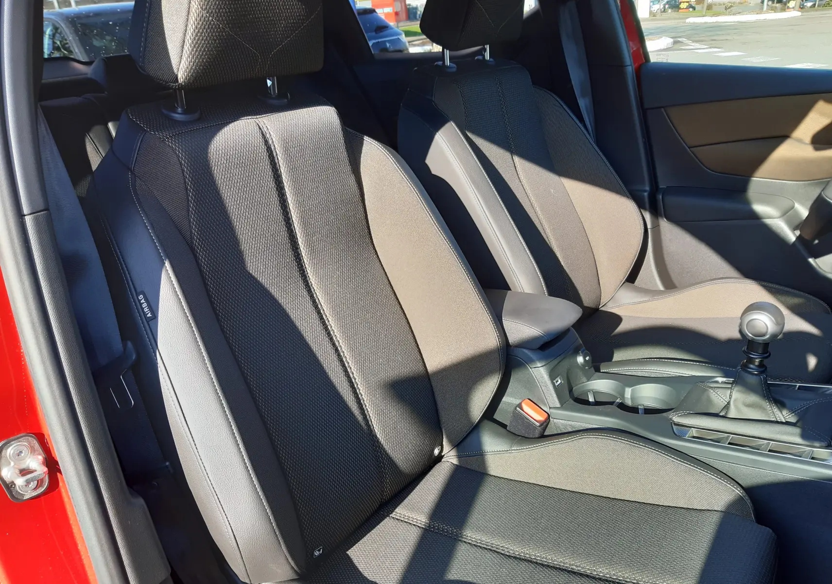 Intérieur du DS3 Crossback 2020 montrant les sièges avant en tissu noir avec coutures apparentes et levier de vitesse manuel.