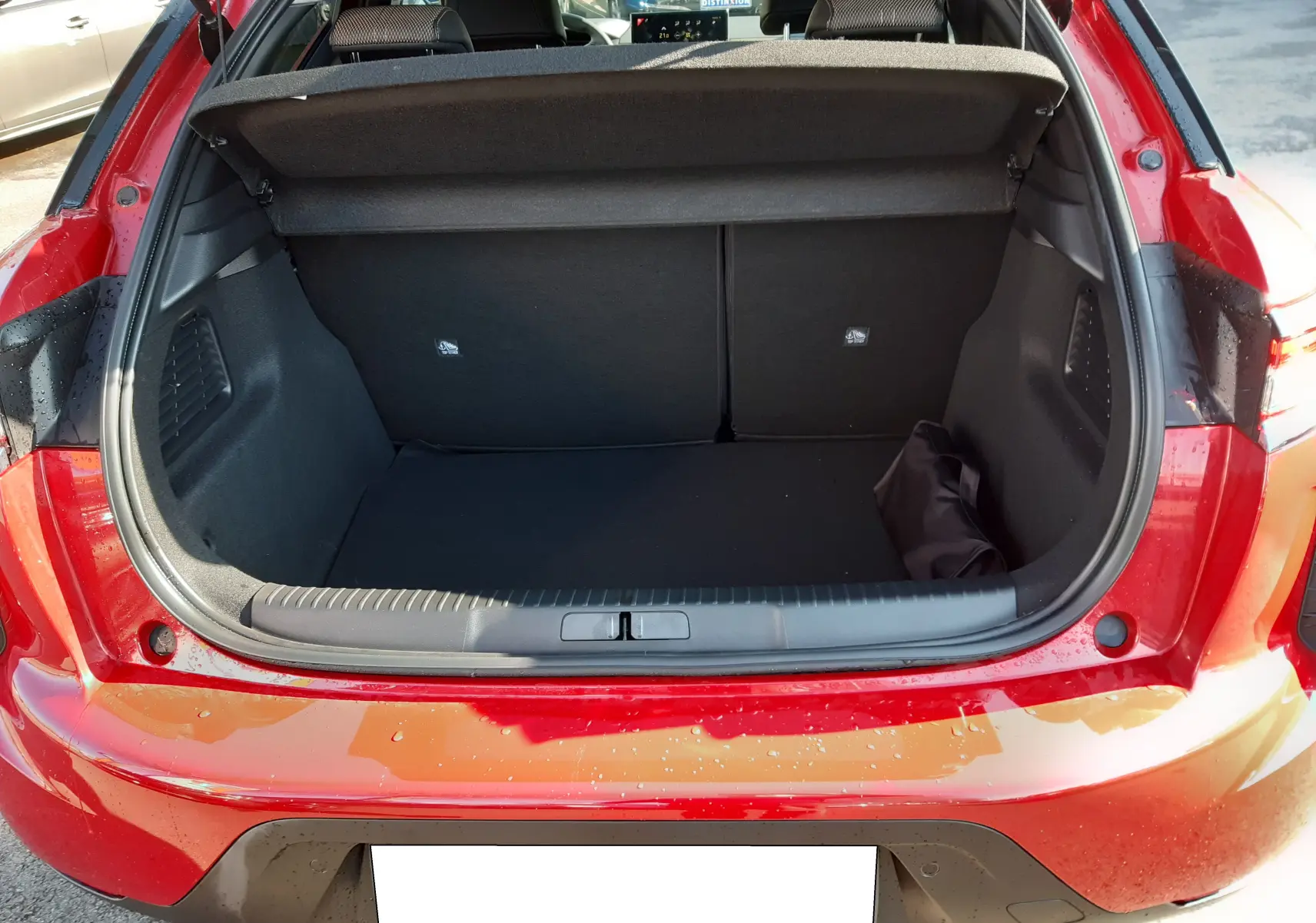 Coffre ouvert vu de l'arrière d'une DS3 Crossback rouge métal avec toit blanc, montrant l'espace de chargement vide.