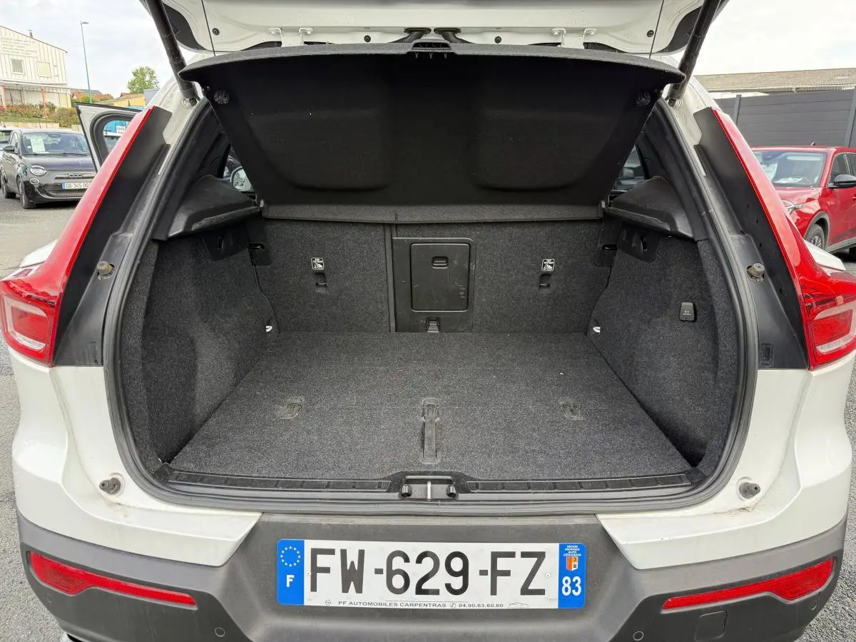 Coffre ouvert vu de l'arrière d'un Volvo XC40 blanc avec feux arrière rouges et plaque d'immatriculation française.