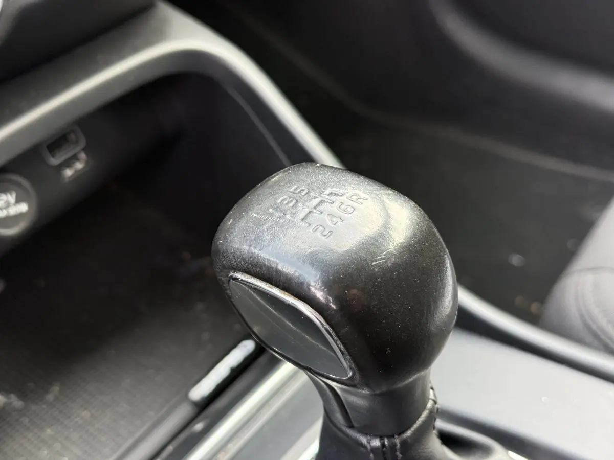 Gros plan sur le pommeau de levier de vitesses manuel noir dans l'habitacle du Volvo XC40 T3 Momentum blanc.