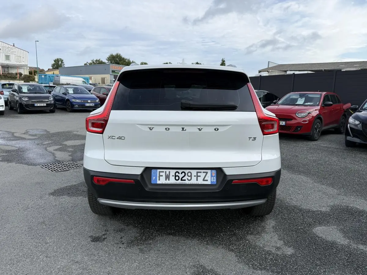 Vue arrière d'un Volvo XC40 T3 blanc avec feux arrière en forme de L et pare-chocs noir contrastant.