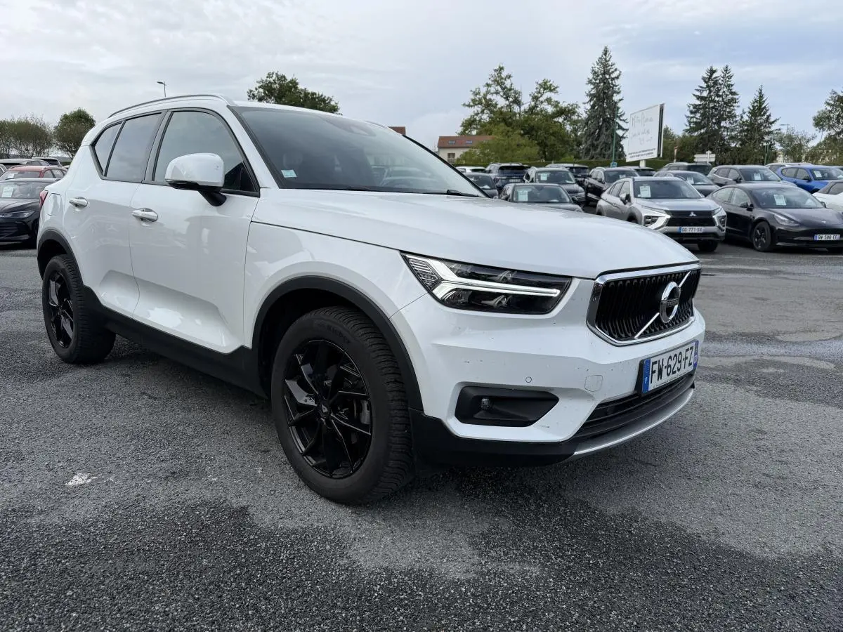 Volvo XC40 blanc en 3/4 avant droit avec jantes alliage noires et calandre chromée sur parking extérieur.