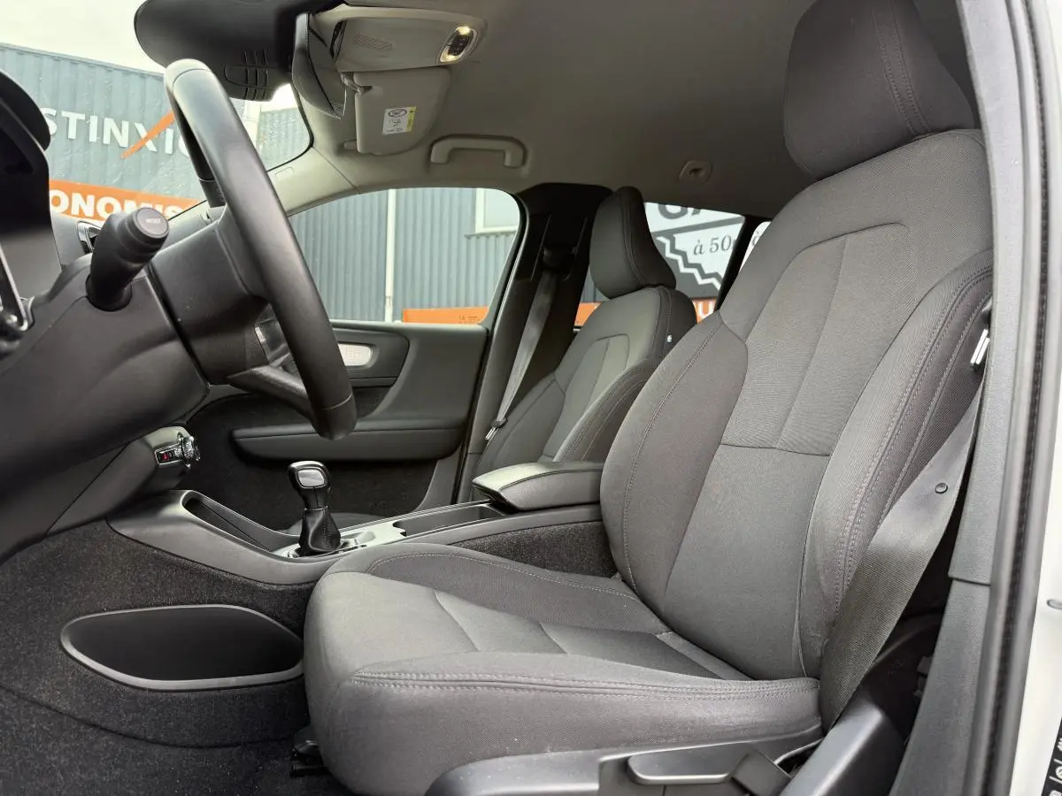 Intérieur côté conducteur du Volvo XC40 blanc 2020, sièges tissu anthracite et levier de vitesses manuel visible.