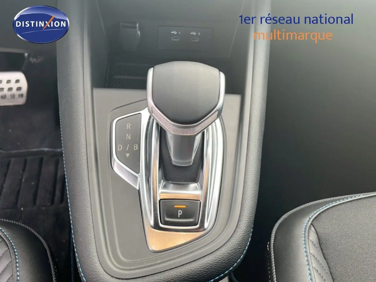 Gros plan sur la commande de boîte automatique noire et chrome dans l'habitacle du Renault Symbioz blanc nacré.