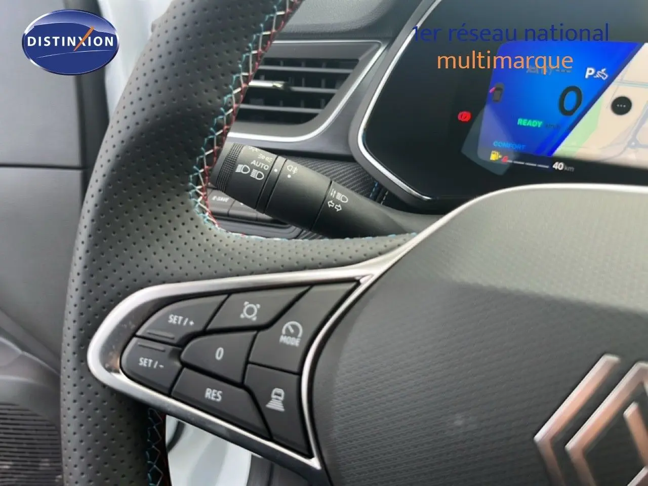 Gros plan sur le volant cuir perforé avec surpiqûres tricolores et commandes intégrées du Renault Symbioz blanc nacré.