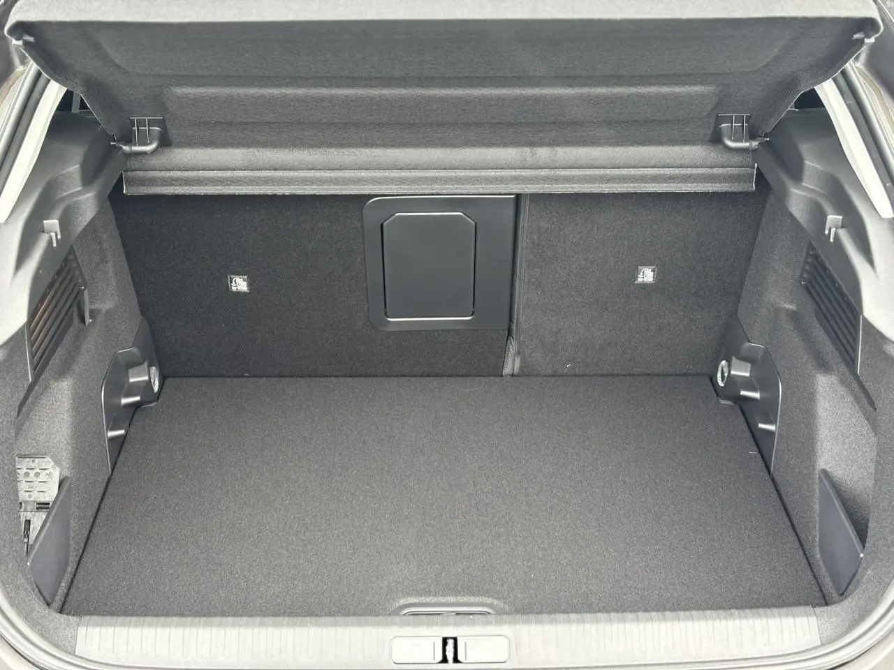 Coffre ouvert vu de l'arrière d'une Citroën C4 2024 gris Platinium, intérieur noir et espace de rangement spacieux.