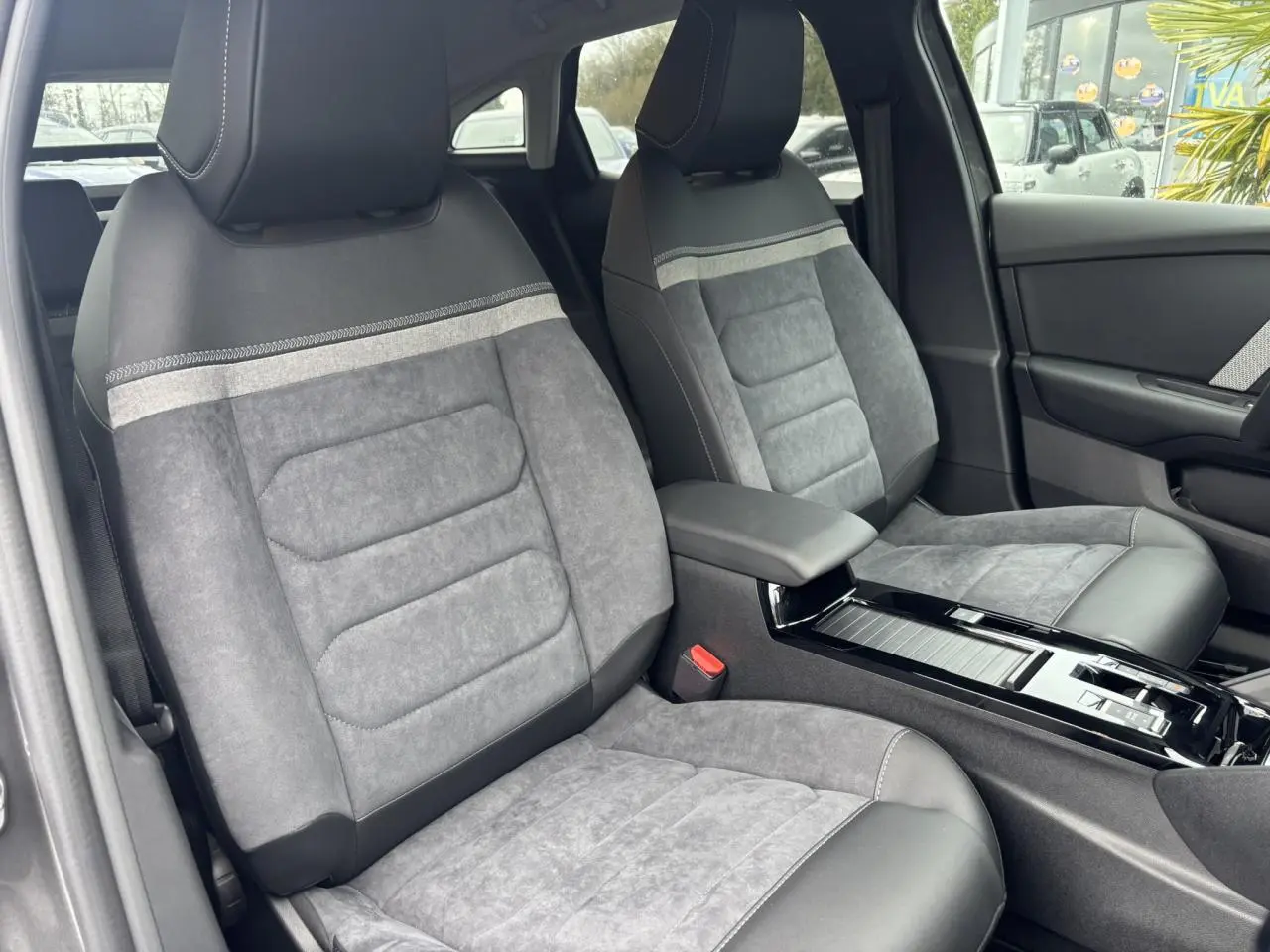 Vue intérieure des sièges avant en Alcantara gris avec accoudoir central et console brillante d'une Citroën C4 2024.