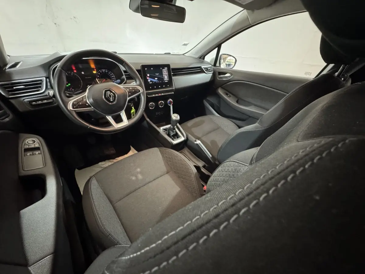 Vue intérieure avant droite de la Renault Clio Business 2020, montrant le volant cuir, écran tactile et sièges tissu noirs.