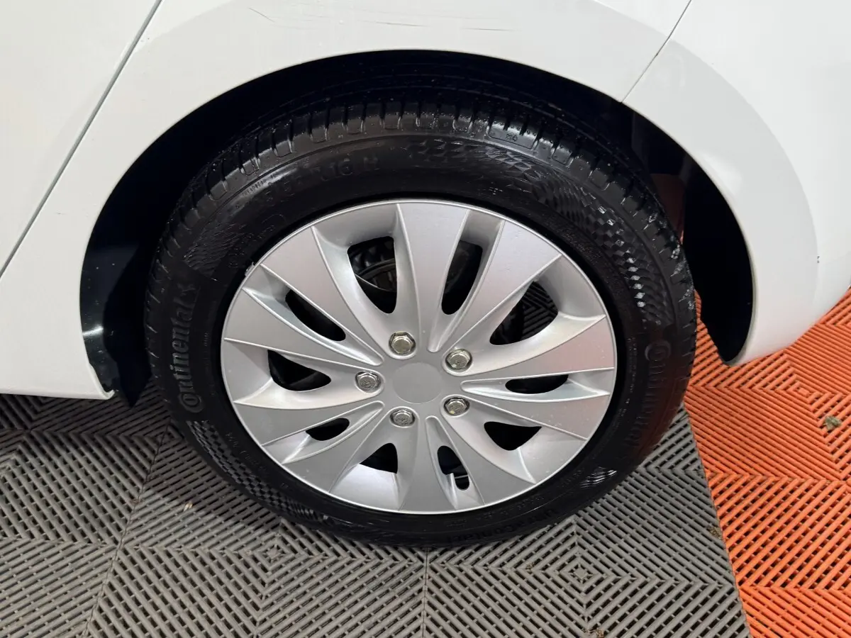 Gros plan sur la roue arrière droite d'une Renault Clio blanche, avec jante en alliage argenté et pneu Continental.