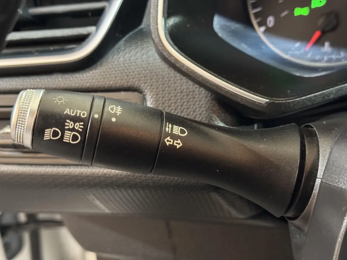 Gros plan sur la manette de commande des phares et clignotants dans l'habitacle d'une Renault Clio Business blanche de 2020.