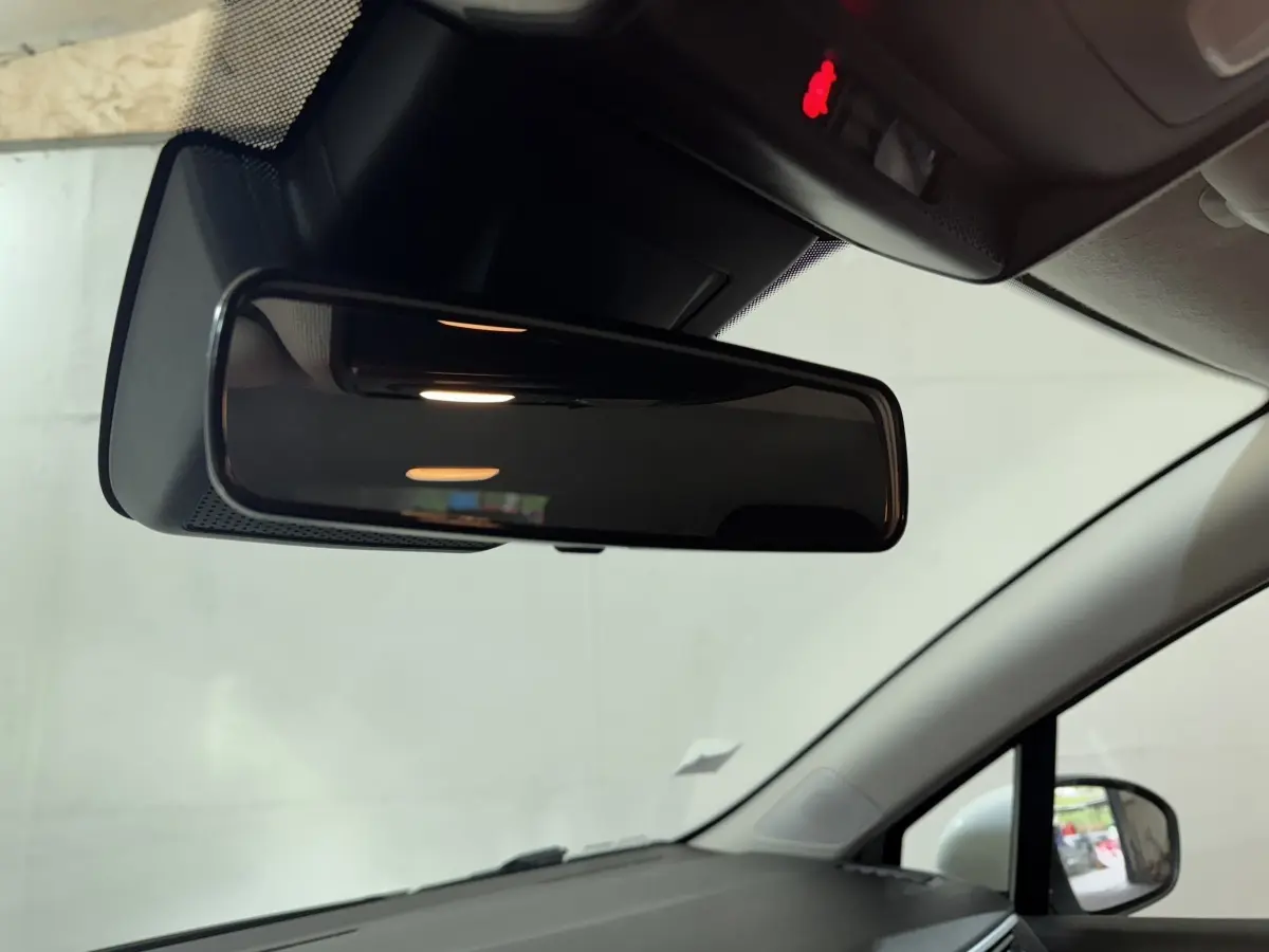 Vue intérieure du rétroviseur central d'une Renault Clio Business TCe 100 blanche, avec rétroviseur extérieur droit visible.