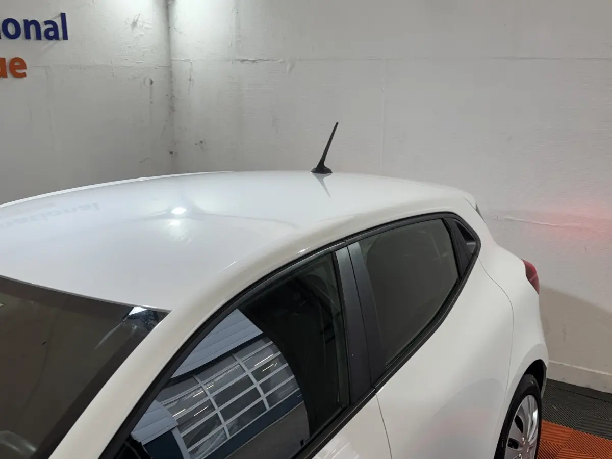 Vue 3/4 arrière droite d'une Renault Clio Business blanche, avec antenne de toit et vitres teintées.