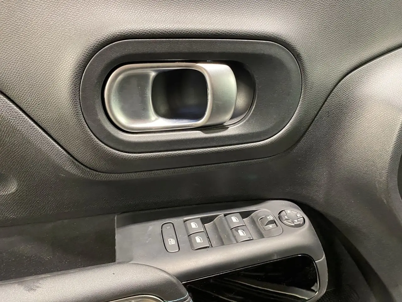 Poignée intérieure de porte côté gauche avec commandes de vitres et rétroviseurs sur Citroën C5 Aircross gris platinium 2023.