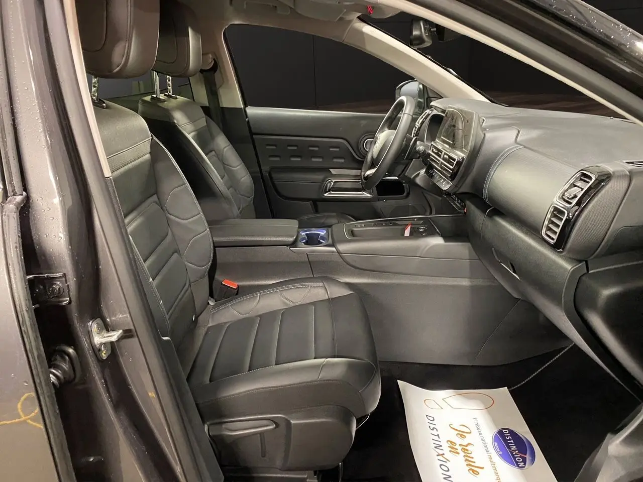 Vue intérieure côté conducteur du Citroën C5 Aircross 2023 gris platinium, sièges noirs en cuir et tableau de bord moderne.