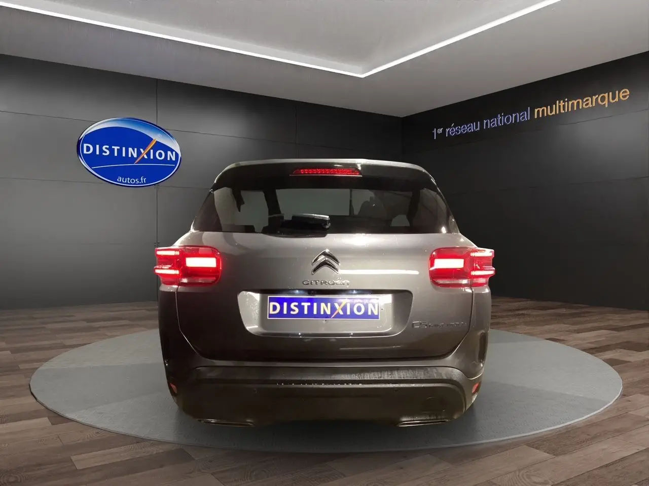 Vue arrière d'un Citroën C5 Aircross gris platinium 2023 avec feux arrière allumés en showroom.
