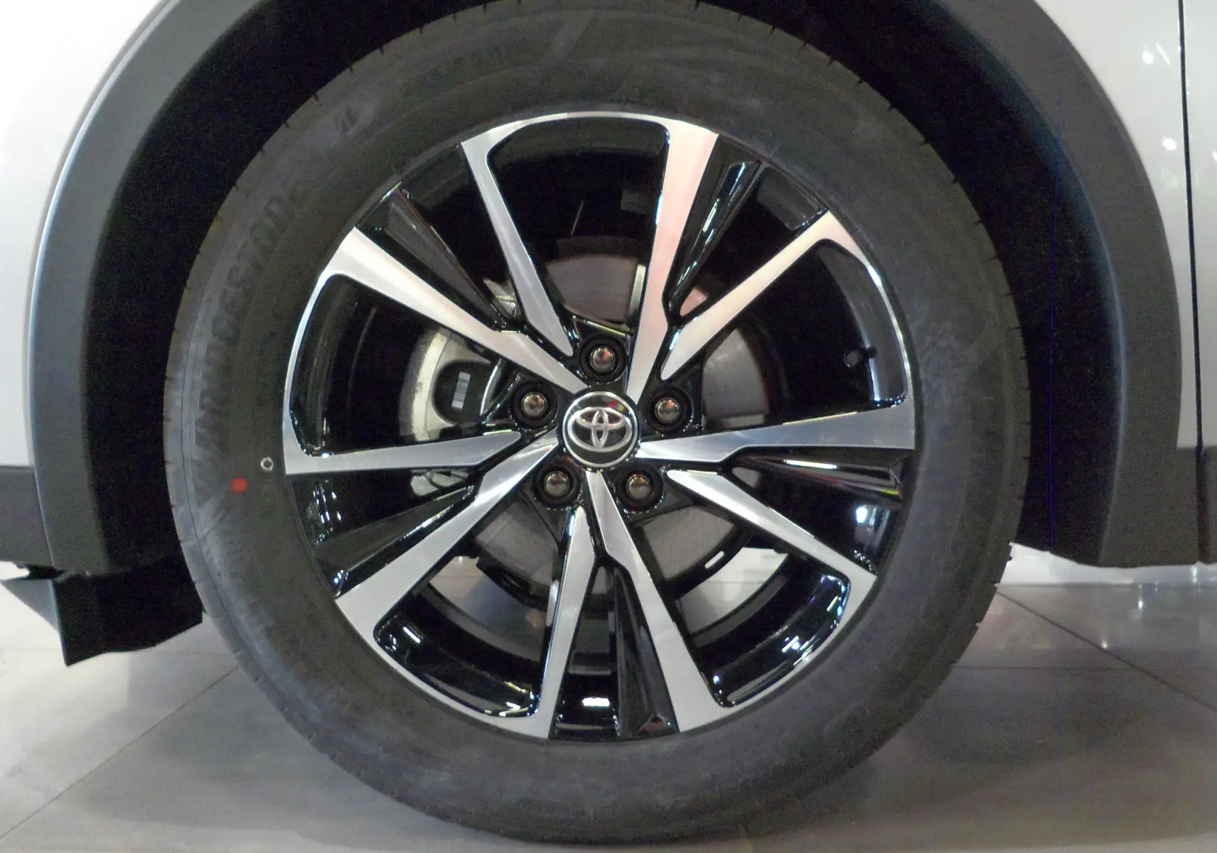 Gros plan sur la jante biton noire et argent du Toyota C-HR Hybride 140 CH Style gris minéral, roue avant droite.