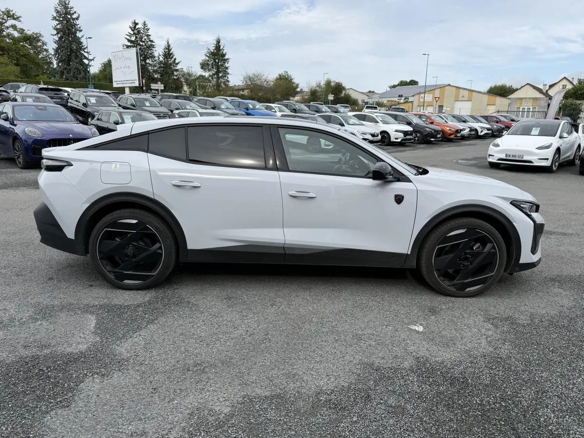 Profil côté gauche d'une Peugeot 408 blanche 2024 avec jantes noires et vitres teintées sur parking.