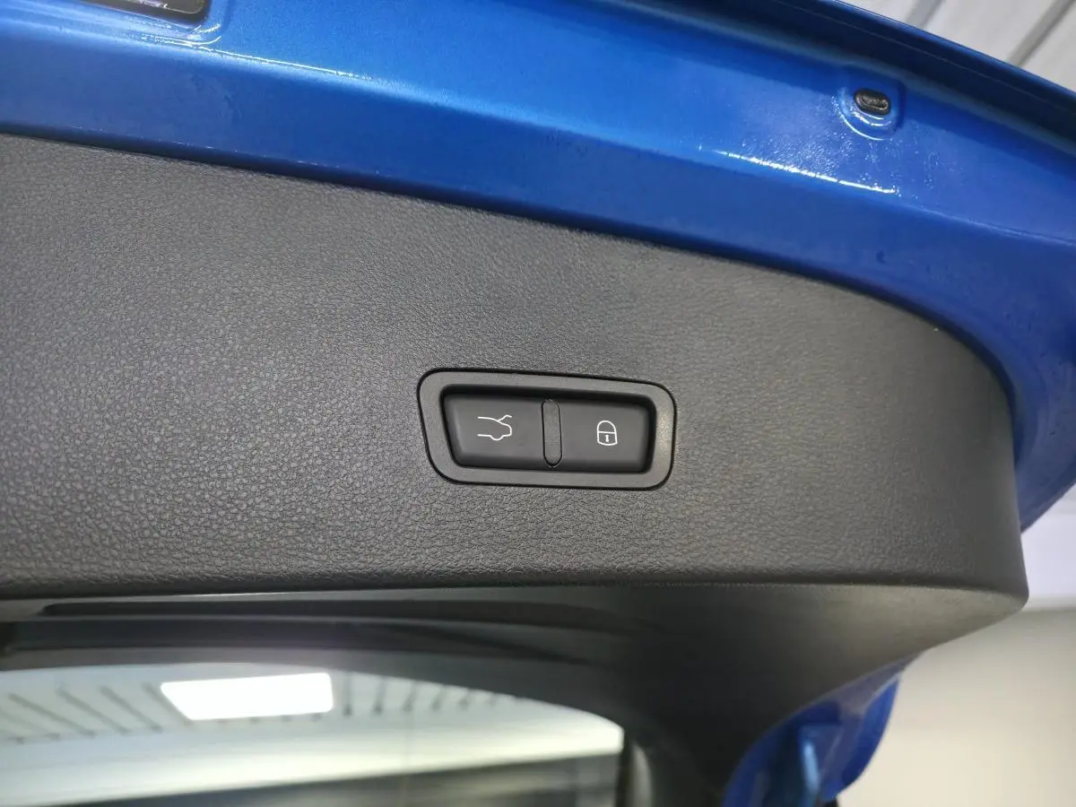 Gros plan sur le hayon électrique bleu de l'Alfa Romeo Tonale avec boutons de fermeture et verrouillage intégrés.