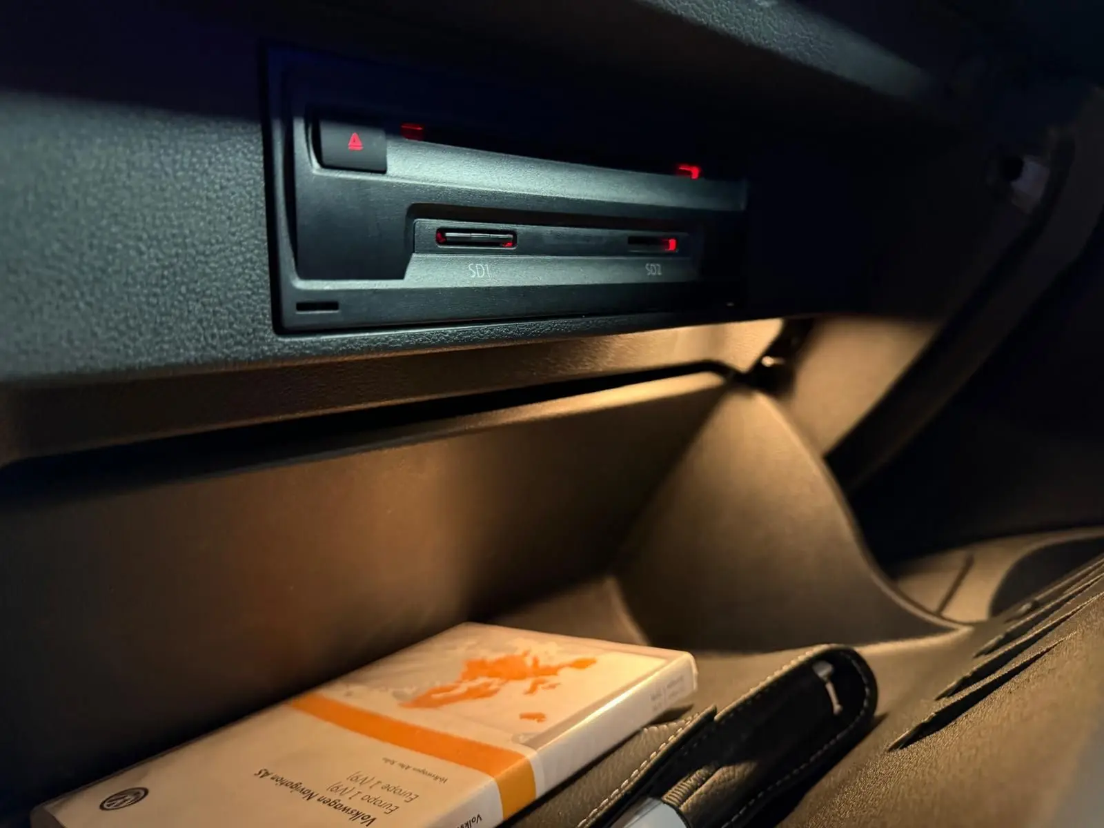 Gros plan sur le compartiment de rangement côté passager du Volkswagen T-Roc 2019, intérieur noir avec manuel d'utilisation.