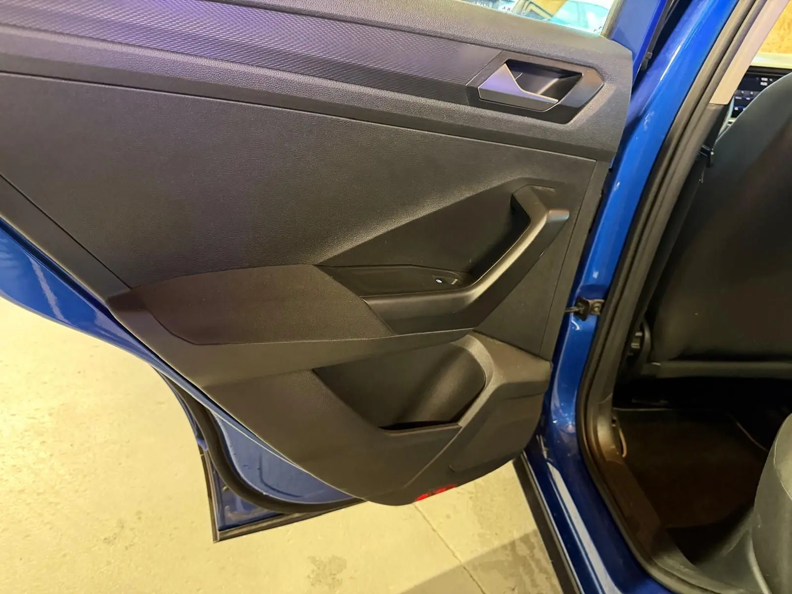 Vue rapprochée de la porte arrière gauche bleu vif du Volkswagen T-Roc 2019 avec intérieur noir et poignée intégrée.