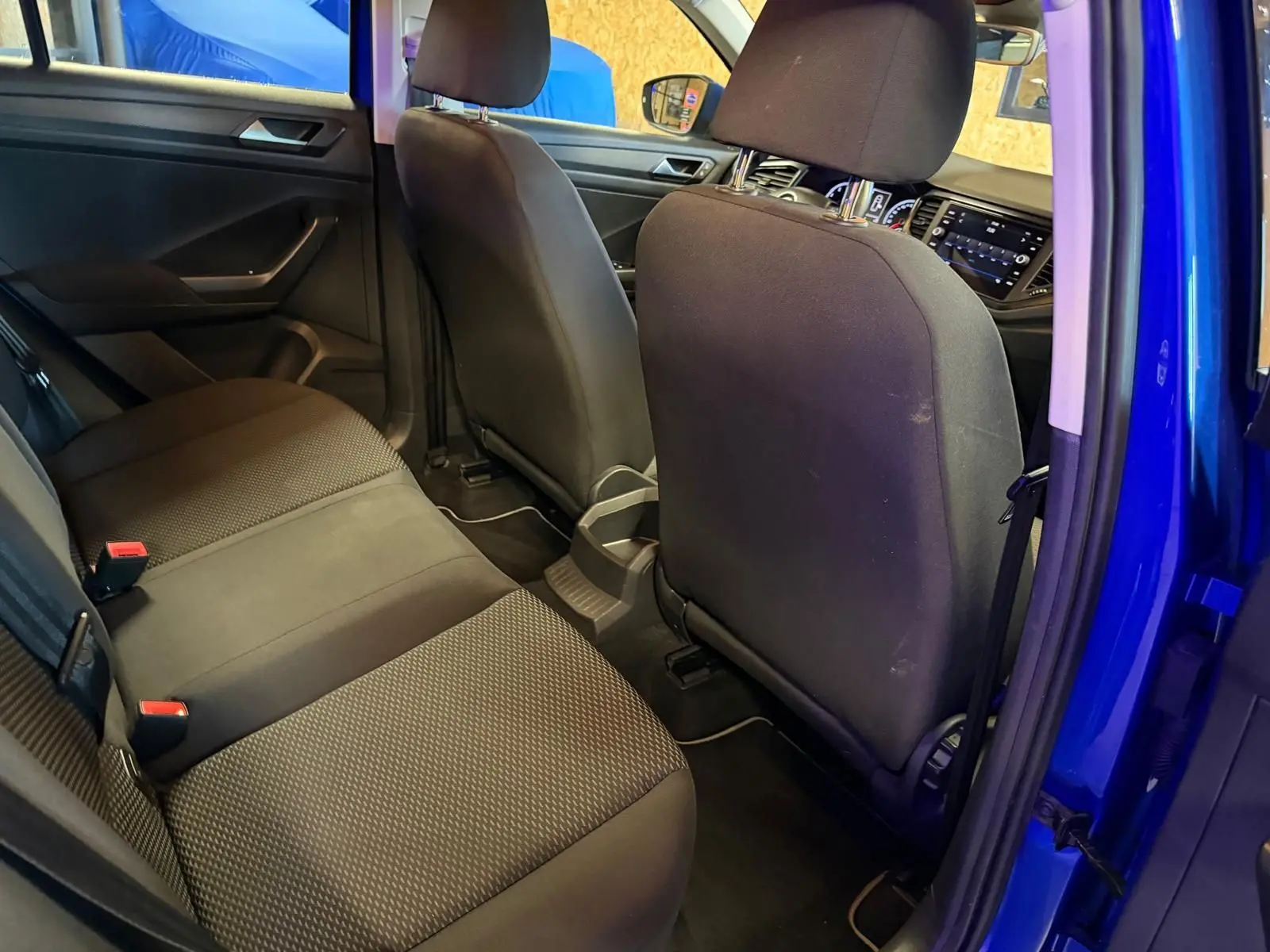 Vue intérieure arrière droite du Volkswagen T-Roc bleu montrant la banquette tissu et les dossiers des sièges avant.