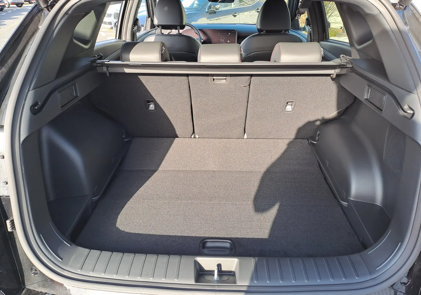 Vue arrière du coffre spacieux du Hyundai Tucson 2025 en Abyss Black, avec banquette arrière rabattable et intérieur noir.