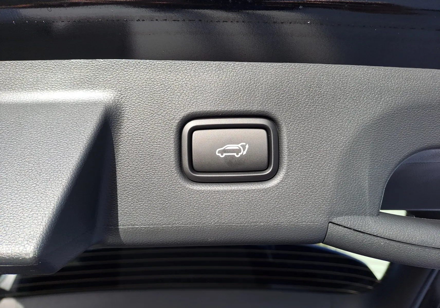 Bouton d'ouverture électrique du hayon sur la garniture intérieure noire du coffre d'un Hyundai Tucson 2025 Abyss Black.