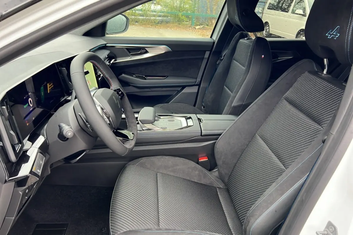 Vue intérieure côté conducteur du Renault Austral ETECH 200 Esprit Alpine Plus 2025 avec sièges noirs et surpiqûres bleues.