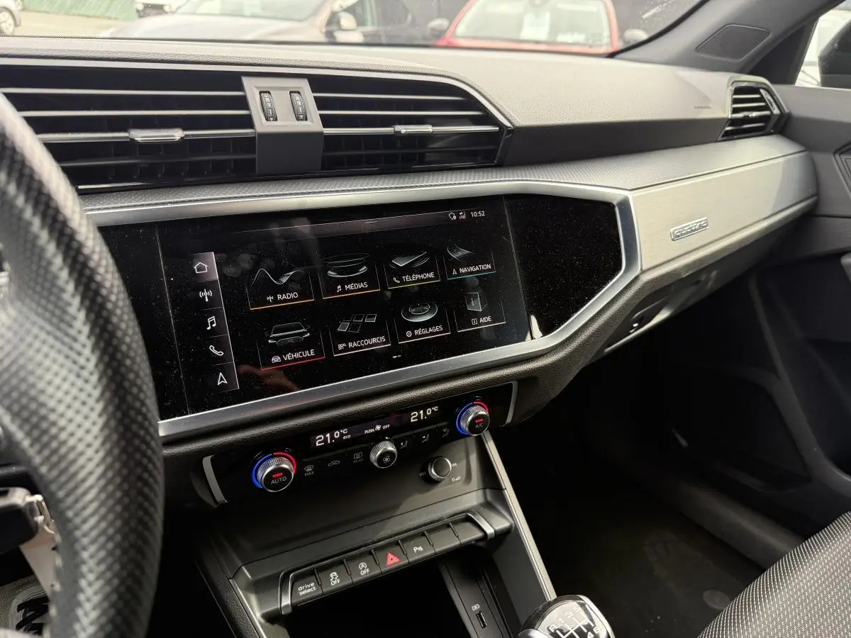Tableau de bord et console centrale de l'Audi Q3 S Line 2019, avec écran tactile et commandes climatisation visibles.