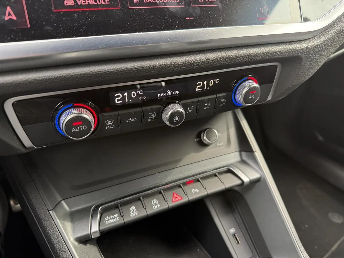 Gros plan sur la console centrale noire de l'Audi Q3 S Line 2019 avec commandes de climatisation automatique et boutons multifonctions.