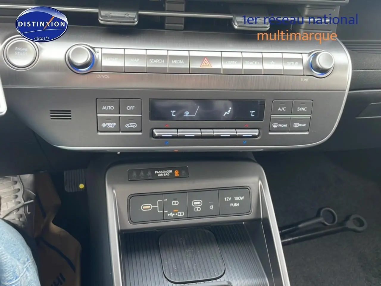 Vue rapprochée de la console centrale du Hyundai Kona 2025 bleu, montrant les commandes clim et recharge sans fil.