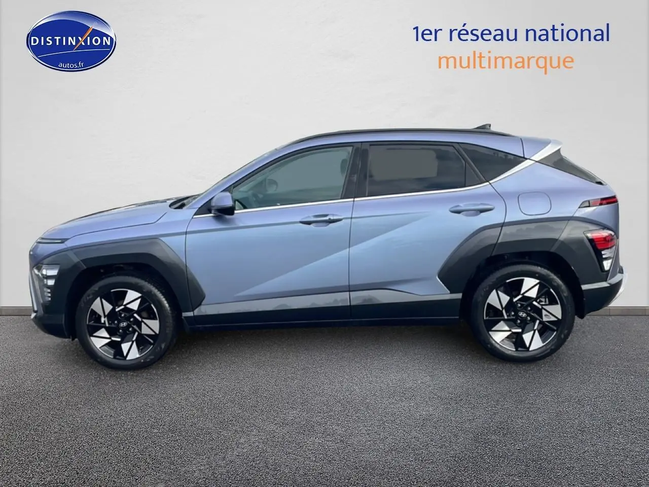 Vue de profil côté gauche d'un Hyundai Kona bleu 2025 avec jantes alliage noires et protections noires sur les ailes.
