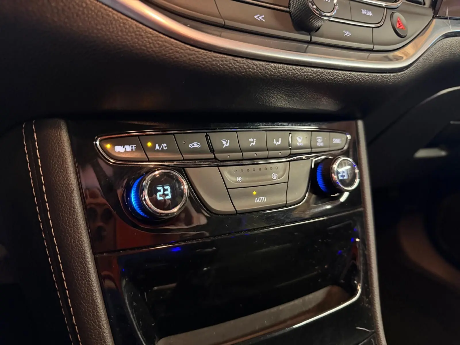 Gros plan sur la console centrale de l’Opel Astra rouge, montrant les commandes de la climatisation automatique bi-zone.