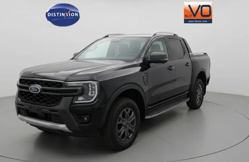 Ford Ranger Wildtrak noir vu en 3/4 avant droit, avec barres de toit, marchepieds et jantes alliage 18 pouces.