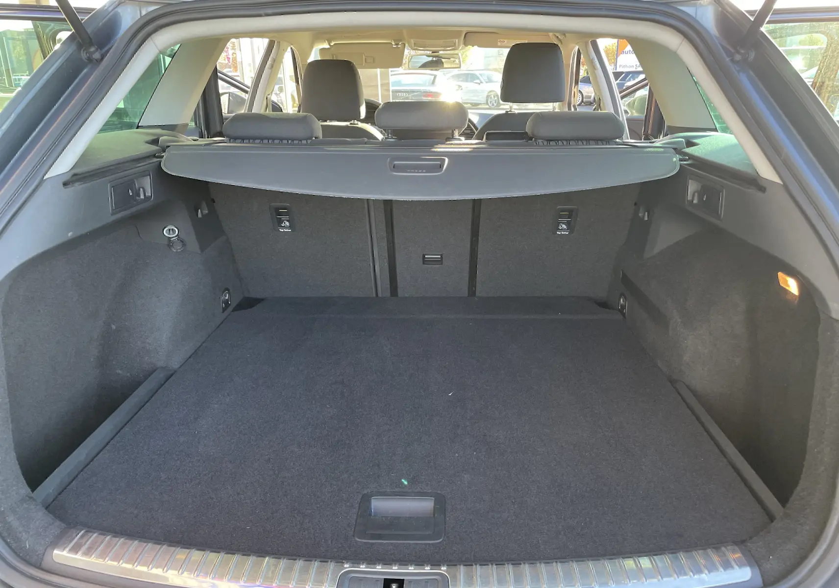 Coffre spacieux ouvert vu de l'arrière d'une SEAT LEON ST gris, avec banquette arrière et cache-bagages visibles.
