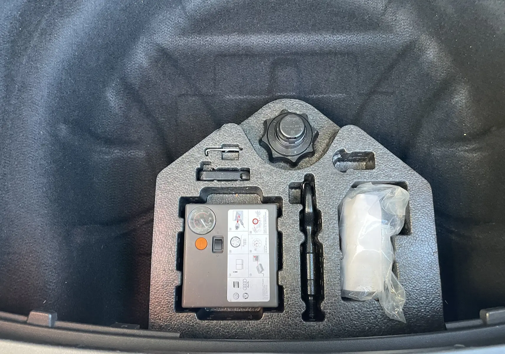 Gros plan sur le kit de réparation pneumatique dans le coffre d'une SEAT LEON ST gris 2013, version 1.2 TSI.